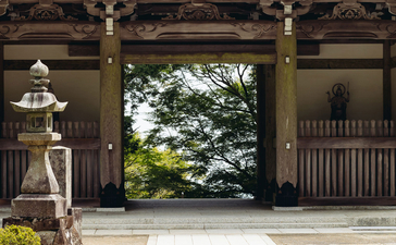 Wooden temple gateway with white floor leading to garden at Amanemu resort.
