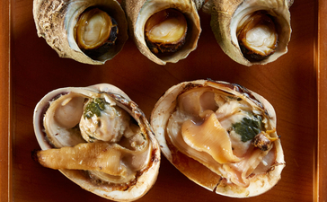 Cinq huîtres fraîches servies dans un plateau en bois à Amanemu, resort côtier japonais.