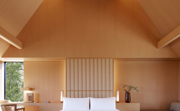 Principal bedroom at Amanemu resort with warm wooden finishes and natural light from skylights.