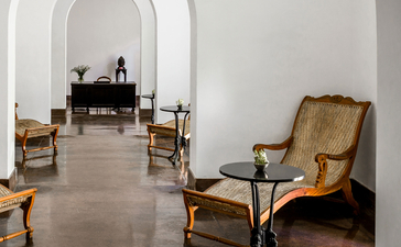 Arched corridor at Amangalla with period furniture and whitewashed walls.