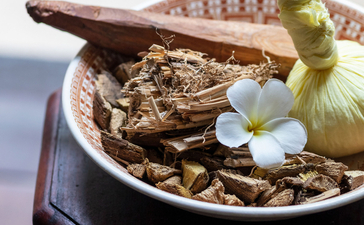 Wooden ornaments and a small white flower arranged in a shallow bowl at Amangalla.