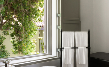 Arched window with garden views beside a bathroom sink at Amangalla.