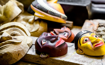 Wooden masks and carved figurines displayed on a weathered surface at Amangalla.
