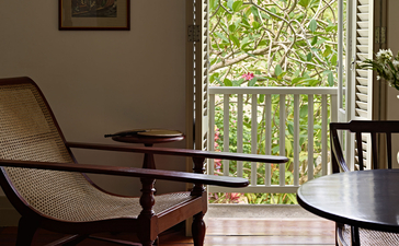 Wooden chairs beside a window with garden views at Amangalla, Sri Lanka.