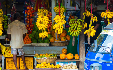 Amangalla flower stall displaying vibrant yellow blooms and orange marigolds from a blue street vendor cart.