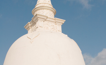 White domed stupa with ornate detailing under blue sky at Amangalla.