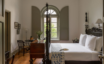 Principal bedroom at Amangalla with arched doorway and period furnishings.