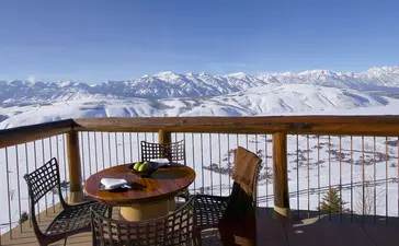 Grand Teton Suite balcony at Amangani with dining table overlooking snow-capped mountain peaks.