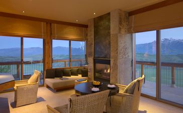 Grand Teton Suite at Amangani with floor-to-ceiling windows framing mountain and lake views at dusk.
