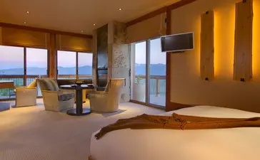 Grand Teton Suite at Amangani with floor-to-ceiling windows framing mountain views and warm interior lighting.