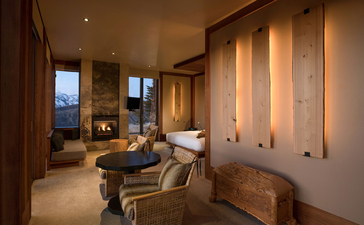 Sena Suite sitting area at Amangani, with warm wood panelling, soft lighting, and views across the landscape.