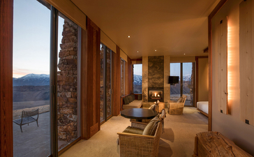 Sena Suite at Amangani with floor-to-ceiling windows overlooking mountain landscape at dusk.