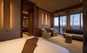 Shoshone Suite at Amangani with bed, seating area and mountain views through floor-to-ceiling windows.