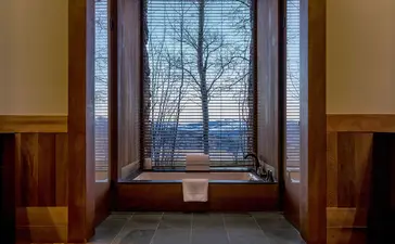 Shoshone Suite at Amangani with winter landscape framed by large windows and wooden furnishings.