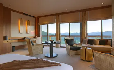 Principal bedroom at Amangani with expansive windows framing mountain views, warm wood finishes, and contemporary furnishings.
