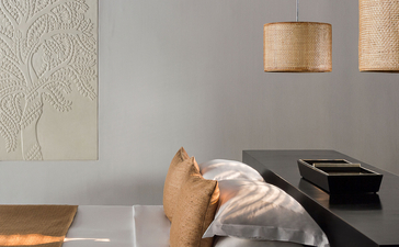 Guest resting on a daybed beneath pendant lights in a spa treatment room at Amansara.
