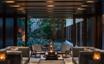 Amansara's open-sided pavilion with seating areas and garden views at dusk.