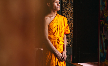Buddhist monk in saffron robes standing in doorway at Amansara.