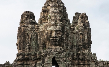 Stone temple tower at Amansara, Cambodia, with carved faces and archway entrance.
