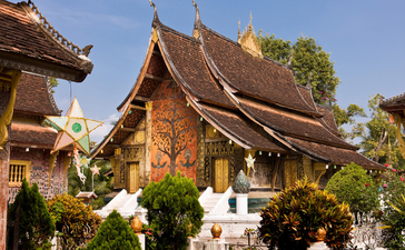Ornate wooden temple with curved roofs and golden details at Amantaka, Laos.