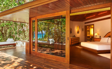 Beach Casita with open wooden doors revealing interior bedroom and covered terrace at Amanpulo, Philippines.