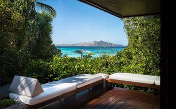 Amanpulo resort casita bedroom with daybed overlooking turquoise waters and distant island, Philippines.