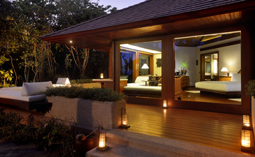 Beach Casita exterior at dusk, Amanpulo resort, Philippines, with warm interior lighting and wooden deck.