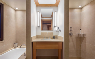 Principal bathroom at Aman Le Mélézin with wooden vanity, dual sinks, and walk-in shower.
