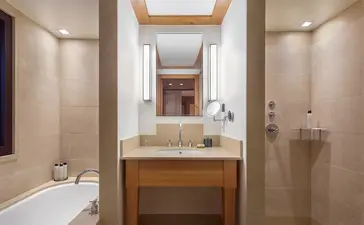 Chambre Village bathroom at Aman Le Mélézin resort with wooden vanity and walk-in shower.