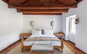 Deluxe Cottage principal bedroom at Aman Sveti Stefan with twin beds and exposed wooden beams.