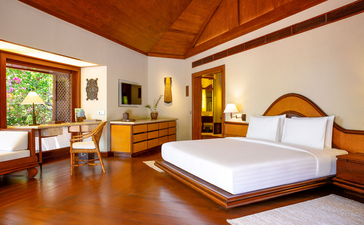 Deluxe Hillside Casita principal bedroom with wooden furnishings and terracotta flooring at Amanpulo resort, Philippines.