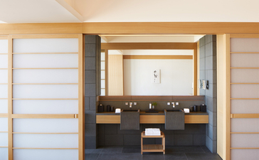Deluxe room bathroom at Aman Tokyo with dual vanities, wooden accents and sliding shoji doors.