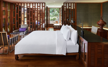 Principal bedroom in an eight-bedroom garden villa at Amanpuri, Thailand, with wooden furnishings and decorative screens.