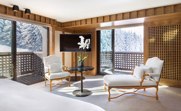 Bright living area at Aman Le Mélézin with wooden screens, contemporary furniture and alpine views through large windows.