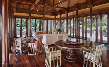 安缦璞瑞度假村的五卧室花园别墅餐厅，木质梁柱和落地玻璃窗环绕，可眺望花园景致。