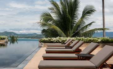 Sunloungers on a terrace overlooking the ocean at Amanpuri resort, Thailand.