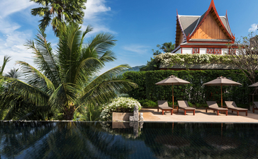 Piscine à débordement bordée de palmiers et d'architecture thaïlandaise traditionnelle à Amanpuri.