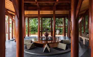 安缦璞瑞度假村五卧海景别墅的圆形起居室，木梁天花板和玻璃门框景观。