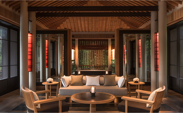 アマノイ リゾートのフォレスト ウェルネス プール ヴィラの開放的なリビング エリア。木製の梁と赤いアクセントが特徴。