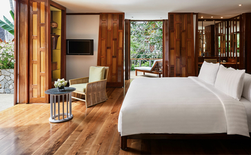 Principal bedroom in a four-bedroom garden villa at Amanpuri resort, with wooden doors opening to views.