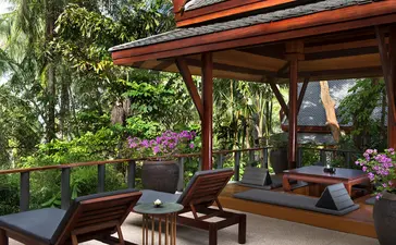 Wooden pavilion with orange-striped canopy at Amanpuri resort, shaded seating area overlooking tropical gardens.