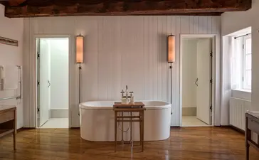 Grand Cottage principal bedroom at Aman Sveti Stefan with freestanding bath and dual ensuite doors.