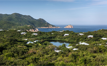Amanoi resort's Lake Pavilion overlooks lush Vietnamese coastline with mountains and turquoise waters.