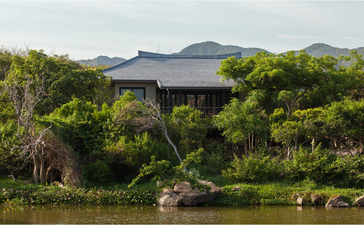 Lake Pavilion at Amanoi resort overlooking water with lush vegetation and mountains beyond.