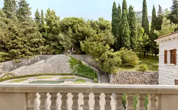 Milocer Garden viewed from a balcony at Aman Sveti Stefan, Montenegro, with cypress trees and manicured grounds.