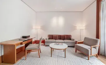 Milocer Garden View Suite lounge at Aman Sveti Stefan, with mid-century furniture and natural light from large windows.