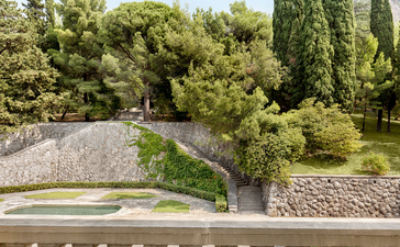 Stone balustrade overlooking manicured gardens with cypress trees at Aman Sveti Stefan, Montenegro.