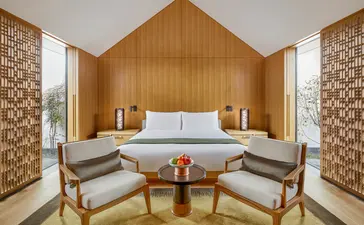 Ming Pavilion bedroom at Amanyangyun featuring a wooden A-frame design with central bed and symmetrical seating areas.