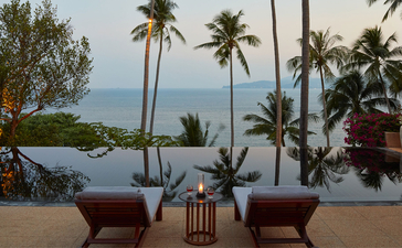 アマンプリのリゾートで、椅子とテーブルが並ぶテラスから、ヤシの木越しに海が見える眺め。