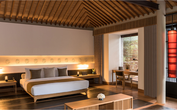 Principal bedroom at Amanoi with wooden ceiling, warm lighting, and Vietnamese coastal views.